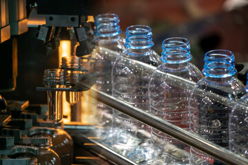 Abstract scene plastic bottle blowing machine and empty PET bottles  on the conveyor belt.