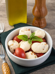 Nozinho or Knot mozzarella, typical brazilian artisanal fresh white cheese with seasonings, basil and cherry tomatoes