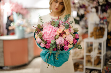 great flower bouquet wrapped in turquoise wrapping paper in woman hands