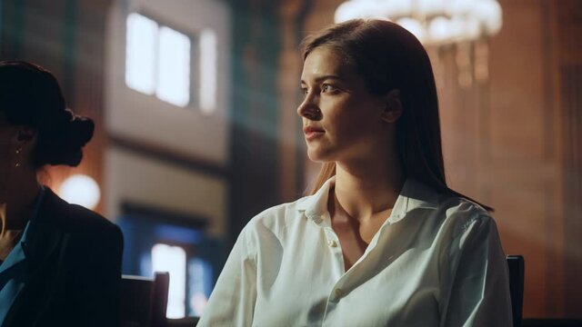 Cinematic Court of Justice Trial: Dramatic Portrait of a Serious Female Victim Sitting Next to Public Defender During Proceedings. Attorney Lawyer Fight for Freedom of Client with Supporting Evidence.