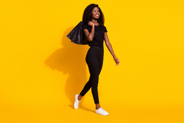 Full size photo of attractive young afro american woman look walk empty space sale bag isolated on yellow color background