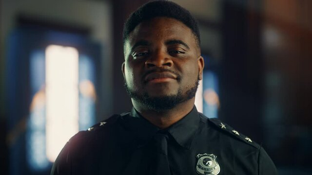 Authentic Portrait of Happy and Handsome Black Policeman in Universal Uniform Smiling at Camera. Successful African American Law Enforcement Agent. Courtroom Security Guard at Work. Cinematic Footage.