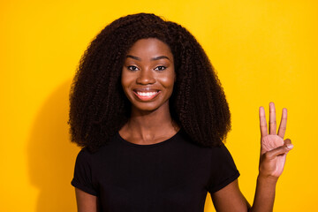 Photo portrait woman smiling happy showing number three fingers isolated bright yellow color...