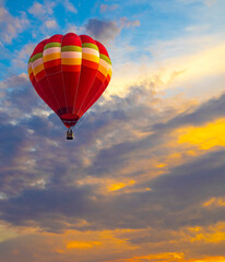 Fototapeta na wymiar Red flying hot air balloon leisure activity against in the sunset sky. Happy and fun people in the basket in the sky
