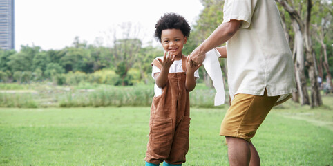 Little African kid boy giving grandfather hands to wipe it dry with tissues after washing hands at green park. Personal hygiene care for children concept