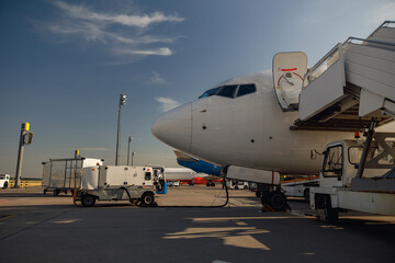 Fototapeta premium White airplane at airport refueling outdoors on a daytime. Aircraft details. Plane, shipping, transportation concept
