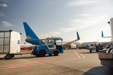 Airfield tractor near big modern airplane. Preparation of aircraft in airport hub on a daytime. Plane, shipping, transportation concept