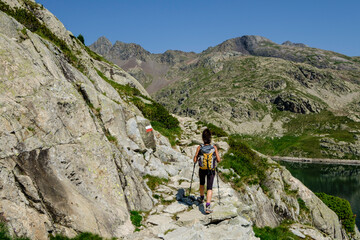 hiker on Bachima&ntilde;a reservoir, Ibones azules and Bachima&ntilde;a alto route, Huesca province, Spain