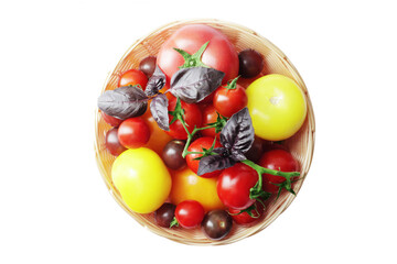 Composition of fresh ripe tomatoes of different varieties in a basket isolated on white background