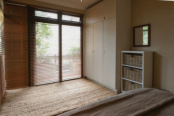 Interior of modern bedroom of comfortable home, with windows to terrace