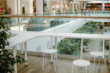 White interior in a shopping center. White table top and chair. Plants in a coffee shop.