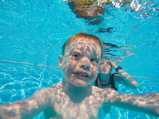 infant is underwater in the pool smiling