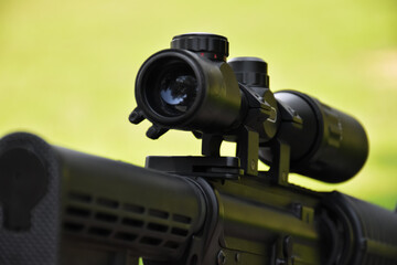 Binoculars of black automatic rifle Long-barreled at the training ground, also known as Air Soft or BB Gun. Use bullets made with spherical plastic beads. Soft and selective focus on binoculars.