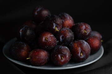 Blurred image of plums in a gray plate on a gray background. Fruit background.