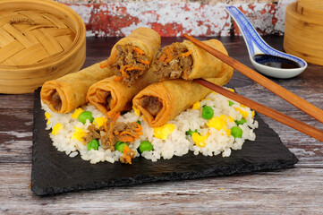 Chinese crispy duck and vegetable filled spring rolls with egg rice on a slate serving board