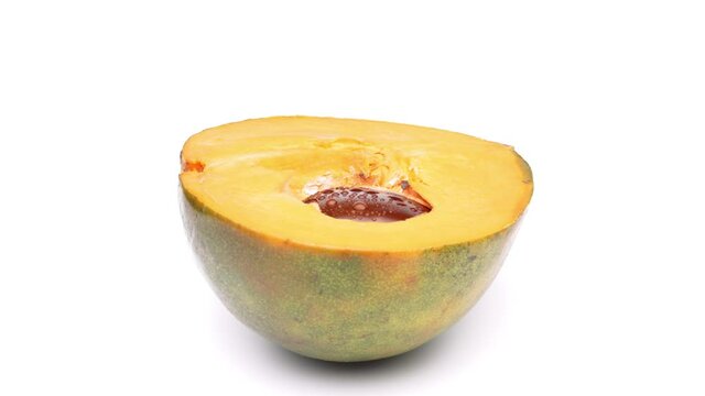 Closeup of one half of lucuma fruit is rotating. Isolated on white background.