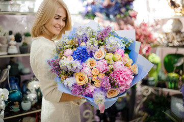 Cheerful woman with wonderful colorful bouquet of various fresh flowers wrapped in paper