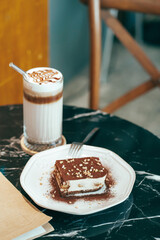 Tiramisu traditional Italian dessert on white plate on dark blue table.