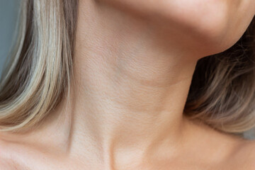 A close-up view of a young woman's neck and collarbone . Lines on the neck. Wrinkles, age-related changes, rings of Venus, goosebumps. Skin care. Close-up - obrazy, fototapety, plakaty