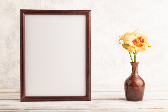 Wooden frame with orange day-lily flowers in ceramic vase on gray concrete background. side view, copy space.