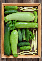 Close-up photo of fresh farm organic green vegetables and greenery. Top view on wooden background
