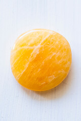 Pierre roulée galet poli de calcite orange sur un fond blanc - Minéral naturel	