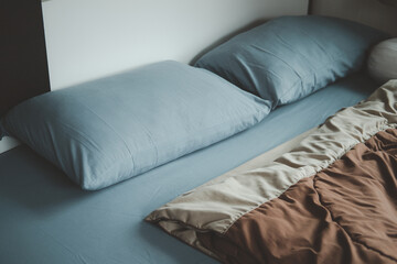 Bed with covered in blue bedding, blue linen and brown duvet