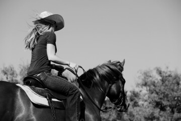 Western lifestyle shows cowgirl horseback riding.