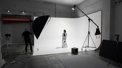Fashion photography in a photo studio. Professional male photographer taking pictures of beautiful woman model on camera, backstage © amixstudio