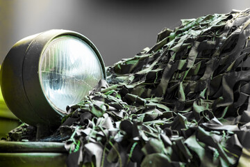 Close-up view of a military vehicle with searchlight and camouflage net