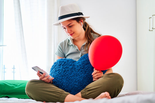 Female teenager with balloon using mobile phone in bedroom