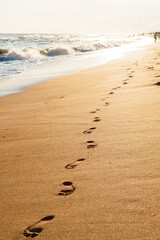 Fototapeta na wymiar footprints on golden sand by the sea in the sun