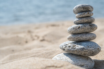 Fototapeta na wymiar Pyramids of gray zen stones on the white sand. Concept of harmony, balance and meditation, spa, massage, relax.