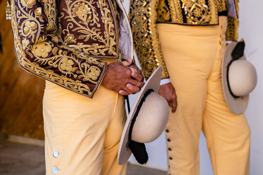Crop bullfighters in yellow costumes standing in stable