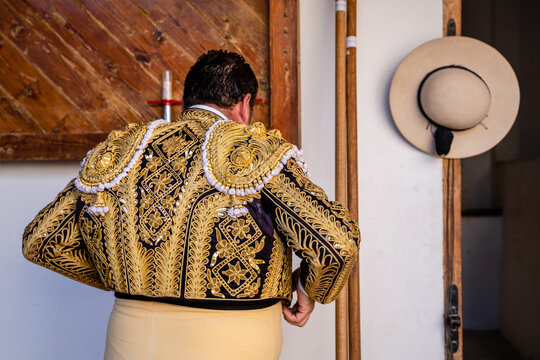 Anonymous bullfighter putting on yellow costume standing in stable