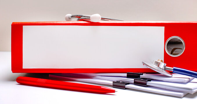 On the desktop there is a stethoscope, a pen, a red folder with files with a place to insert text. Medical concept