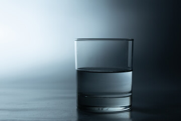 Half glass of water on a black and white background with a shadow below