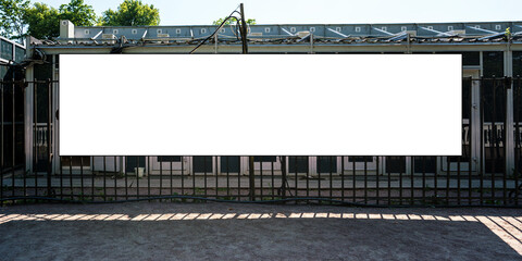 Empty white huge horizontal billboard hangs on metal fence