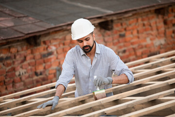 The young builder works on an unfinished roof
