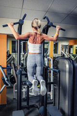 Working out the muscles of the back, chest, triceps and shoulders. A girl of athletic physique on a...