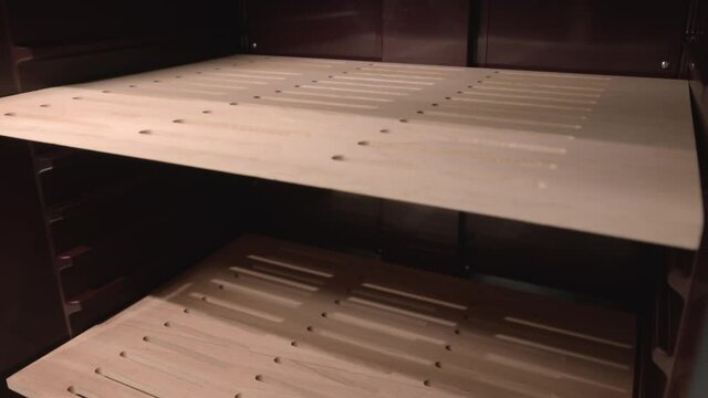 Motion along empty wooden shelves inside new refrigerator for stores and restaurants in light room extreme close view