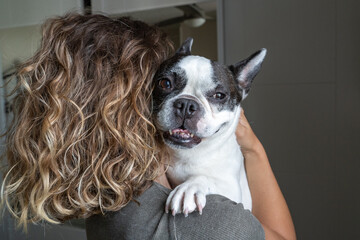 Unrecognizable woman dog lover with bulldog at home. Horizontal view of woman holding baby dog indoor
