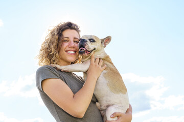 Portrait of woman dog lover hugging baby bulldog. Horizontal view of woman with pet. Lifestyle with animals outdoors.