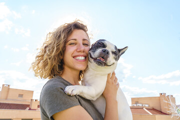 Happy woman holding bulldog. Horizontal view of woman with pet outdoors. Lifestyle with animals. - Powered by Adobe