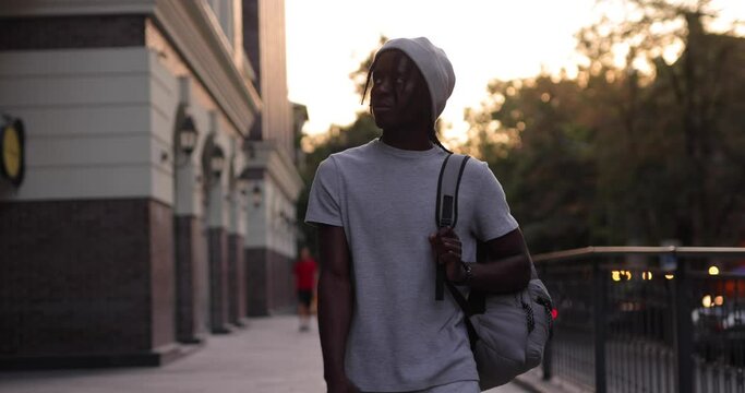 African American man walking in a city street with backpack, super slow motion
