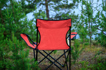 Lovely place. red tourist folder chair in the spruce forest