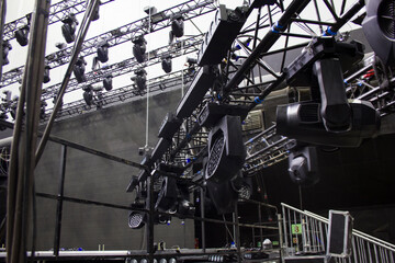 Moving head spotlight devices are clamped on a rigging steel trusses. Installation of professional...