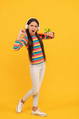 unhappy child skateboarder listen music in headphones with penny board skateboard, hipster