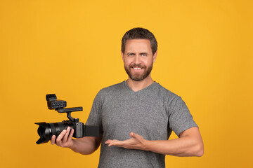 happy bearded man videographer presenting professional camcorder, product proposal