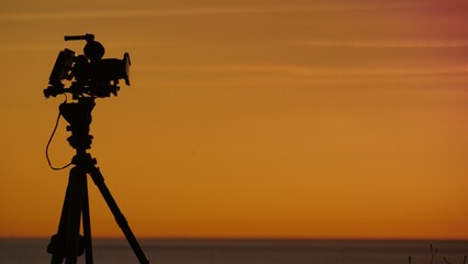 Camera taking picture of sunrise over sea